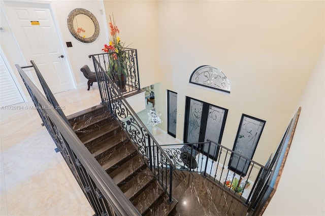 stairs featuring a towering ceiling and french doors