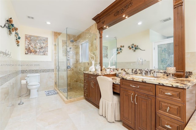 bathroom featuring an enclosed shower, vanity, toilet, and tile walls