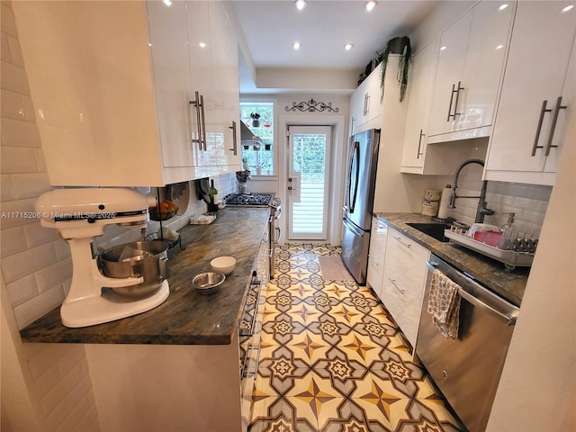 kitchen with sink, light tile patterned floors, backsplash, white cabinets, and appliances with stainless steel finishes