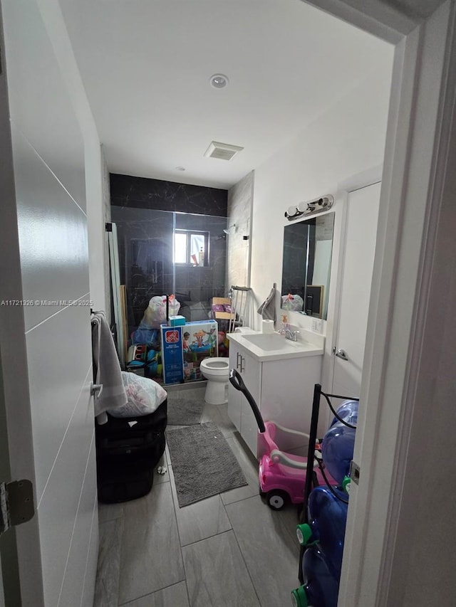 bathroom with vanity, toilet, and tiled shower