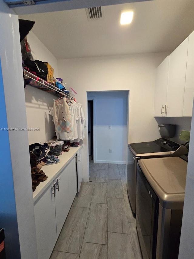 clothes washing area with cabinets and independent washer and dryer