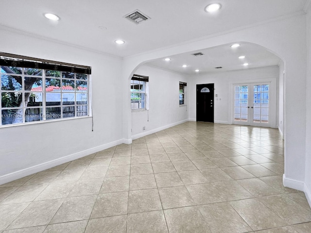 empty room featuring light tile patterned floors, french doors, and ornamental molding