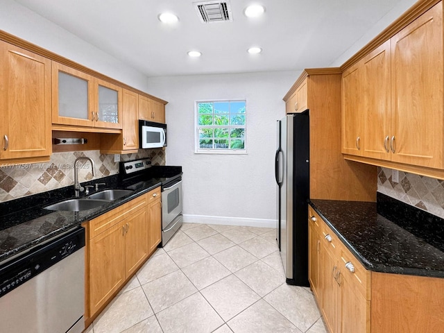 kitchen with backsplash, sink, dark stone counters, and appliances with stainless steel finishes