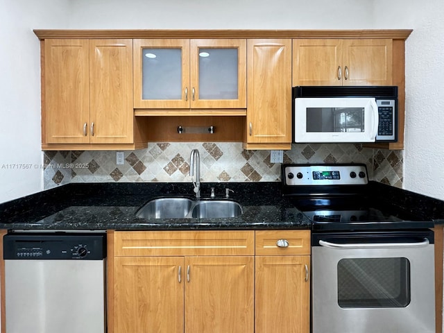 kitchen with stainless steel appliances, tasteful backsplash, dark stone counters, and sink