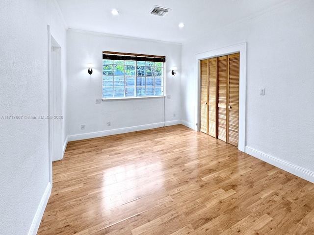 unfurnished bedroom with a closet, crown molding, and light hardwood / wood-style flooring