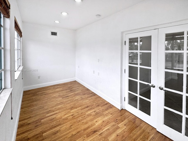 spare room featuring hardwood / wood-style floors and french doors