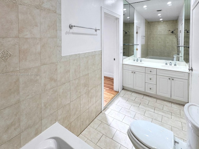 full bathroom with tile patterned flooring, separate shower and tub, toilet, vanity, and tile walls