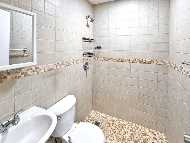 bathroom with toilet, a tile shower, and sink