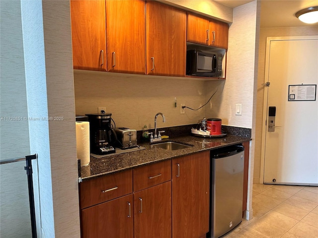 kitchen featuring stainless steel dishwasher, light tile patterned floors, sink, and dark stone counters