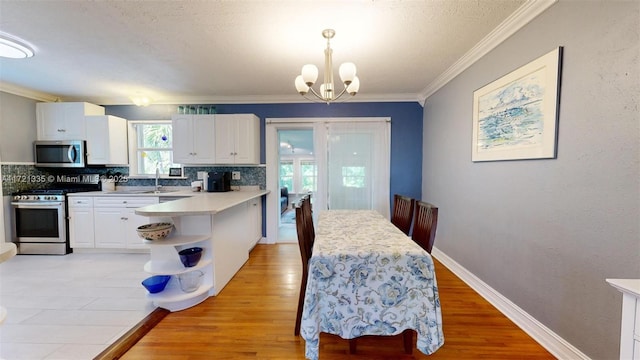 kitchen with decorative light fixtures, white cabinets, kitchen peninsula, stainless steel appliances, and an inviting chandelier