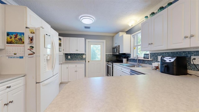 kitchen with stainless steel appliances, white cabinetry, sink, and tasteful backsplash