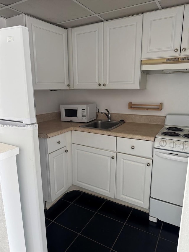 kitchen featuring white cabinets, white appliances, dark tile patterned flooring, and sink