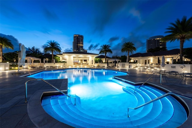 pool at dusk featuring a patio