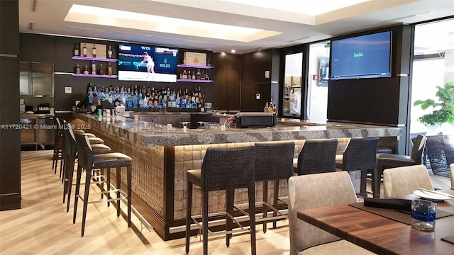 bar with light hardwood / wood-style floors and a wall of windows