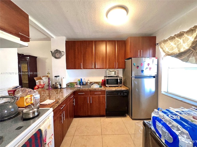 kitchen with appliances with stainless steel finishes, a textured ceiling, light tile patterned floors, and dark stone counters