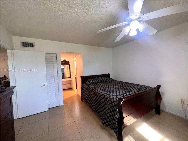 bedroom featuring ceiling fan, light tile patterned floors, and a textured ceiling