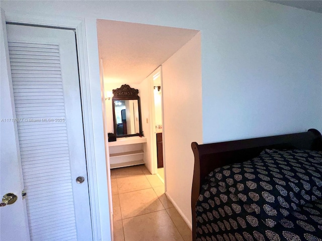 bedroom with ensuite bath, light tile patterned floors, and a closet