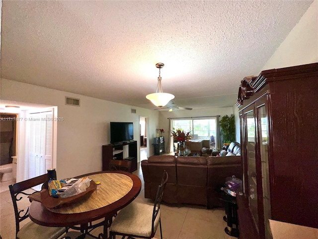 dining space featuring ceiling fan, light tile patterned flooring, and a textured ceiling