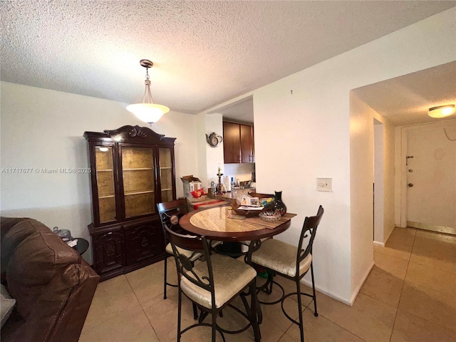 dining area featuring light tile patterned flooring and a textured ceiling