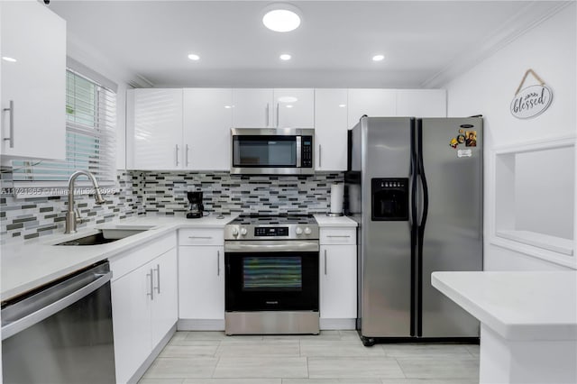 kitchen with sink, decorative backsplash, ornamental molding, appliances with stainless steel finishes, and white cabinetry