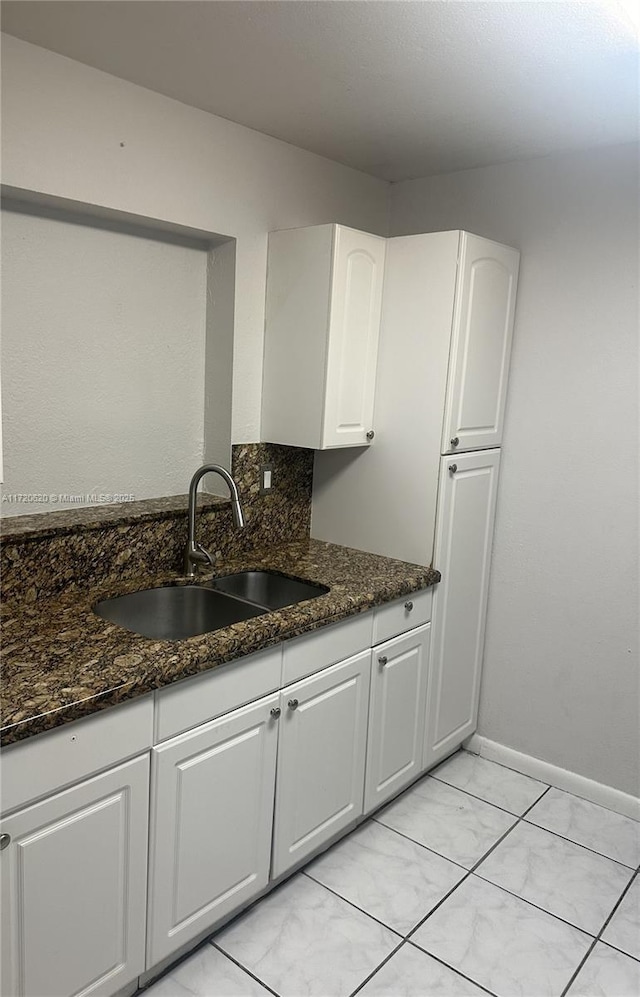 kitchen with sink, white cabinets, dark stone counters, and tasteful backsplash