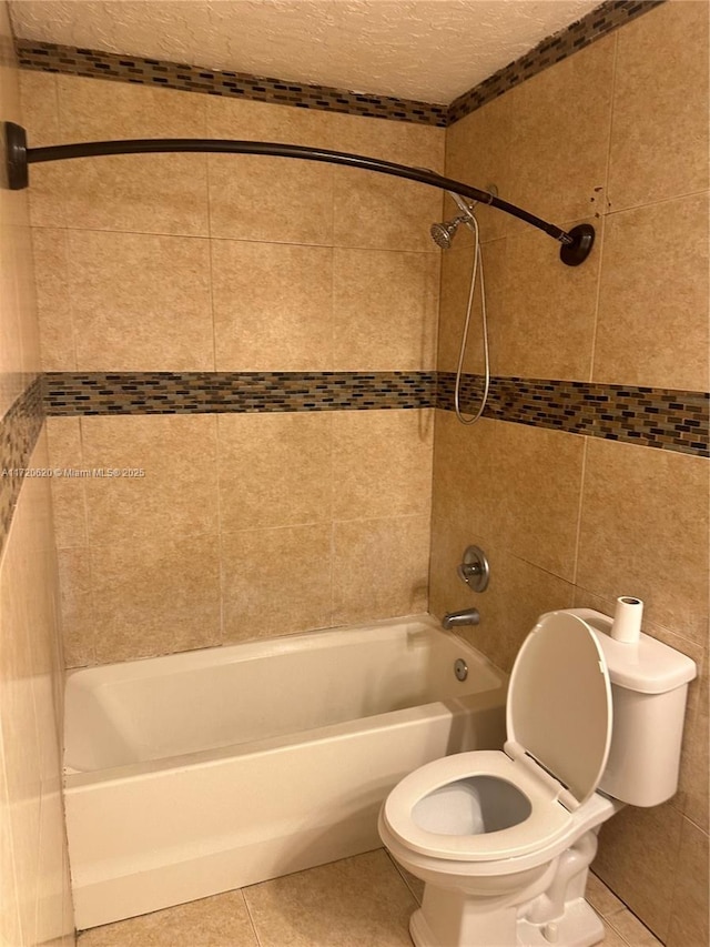 bathroom with toilet, tiled shower / bath, and tile patterned flooring