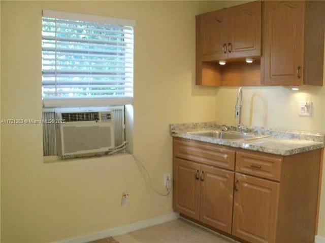 kitchen with light tile patterned flooring, light stone counters, and sink