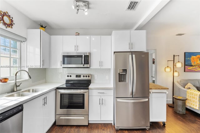 kitchen featuring white cabinetry, sink, dark wood-type flooring, backsplash, and appliances with stainless steel finishes