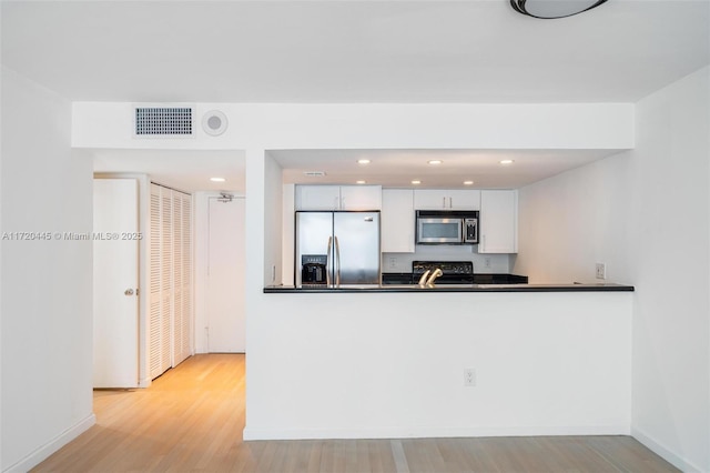 kitchen featuring white cabinetry, stainless steel appliances, kitchen peninsula, and light hardwood / wood-style floors