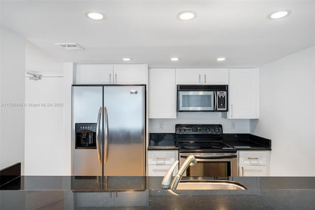 kitchen with sink, dark stone counters, white cabinets, and appliances with stainless steel finishes