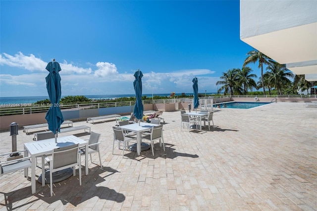 view of pool with a water view and a patio