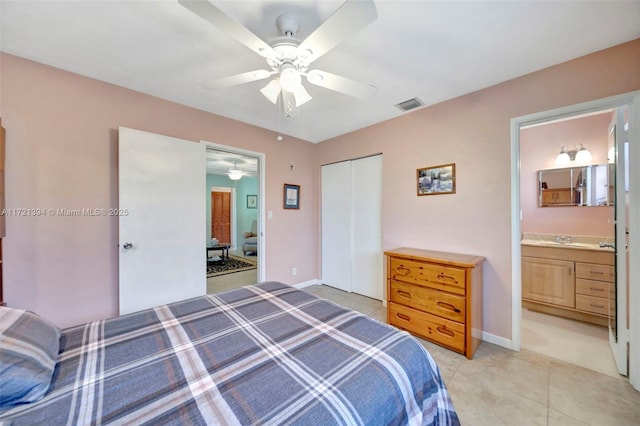 bedroom with sink, ensuite bath, ceiling fan, light tile patterned flooring, and a closet