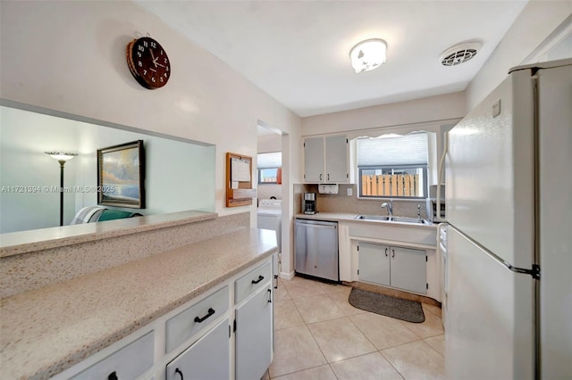 kitchen with stainless steel dishwasher, white fridge, white cabinets, and sink