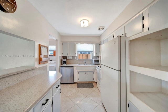 kitchen with dishwasher, light tile patterned floors, white fridge, washer / dryer, and range