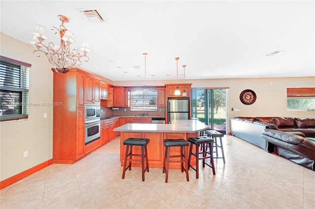 kitchen featuring sink, hanging light fixtures, a kitchen island, a kitchen bar, and stainless steel appliances