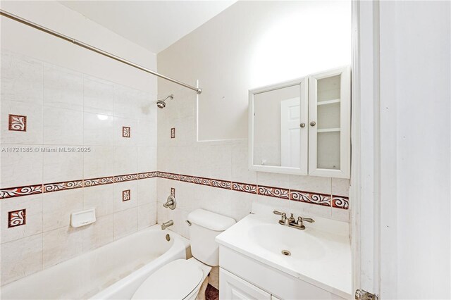 full bathroom with tiled shower / bath, vanity, toilet, and tile walls