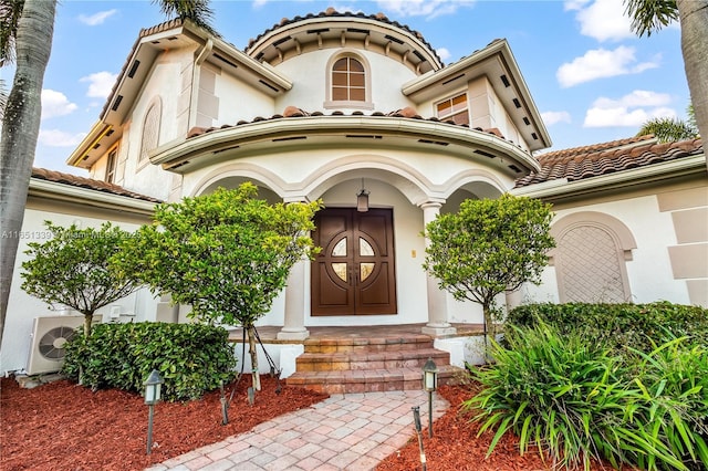 property entrance featuring a tile roof and stucco siding