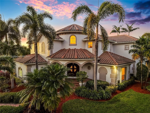 mediterranean / spanish house featuring a tiled roof and stucco siding