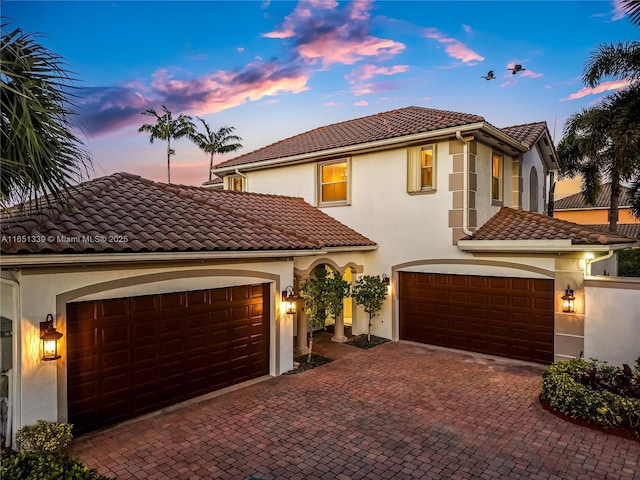 mediterranean / spanish house with a tiled roof, decorative driveway, and stucco siding