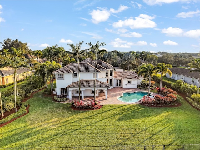 back of property with a fenced in pool, a patio, fence, a yard, and stucco siding