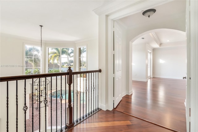 hallway with ornamental molding, arched walkways, dark wood-type flooring, and baseboards