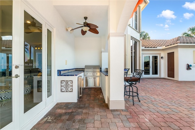 view of patio / terrace with french doors, ceiling fan, grilling area, and an outdoor kitchen