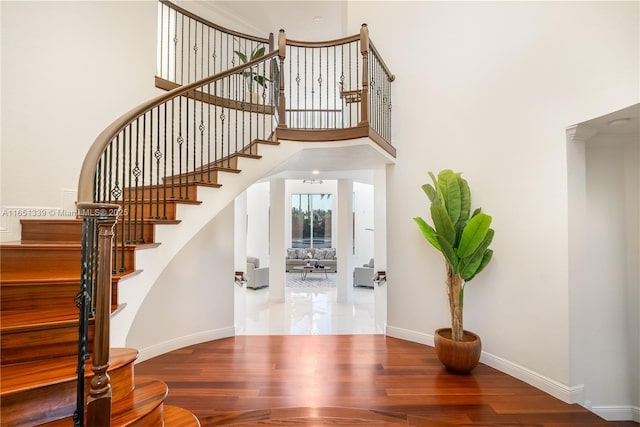 stairs with baseboards, a high ceiling, and wood finished floors