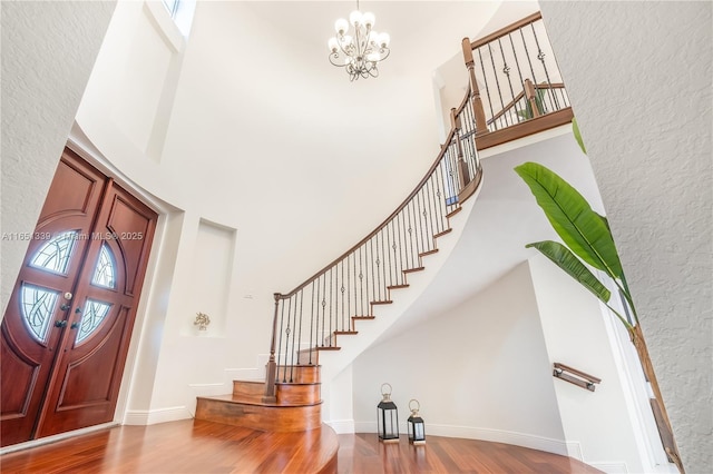 foyer entrance featuring a high ceiling, stairway, and wood finished floors