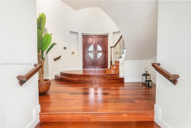 entrance foyer featuring baseboards, stairway, vaulted ceiling, and wood finished floors