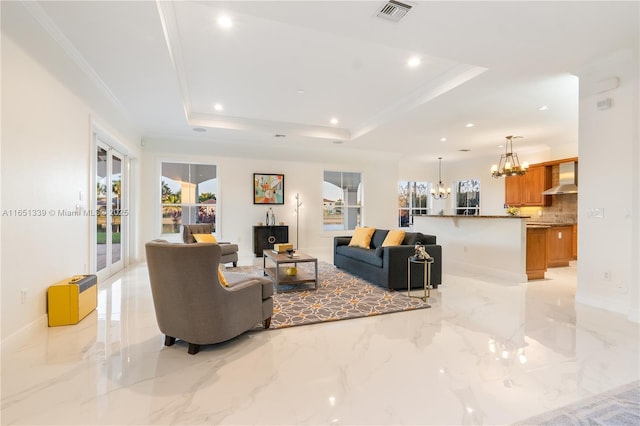 living room with crown molding, a raised ceiling, visible vents, and an inviting chandelier