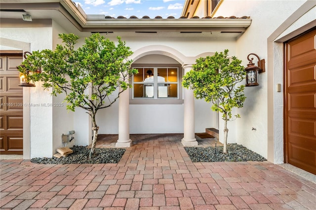 entrance to property featuring a garage and stucco siding