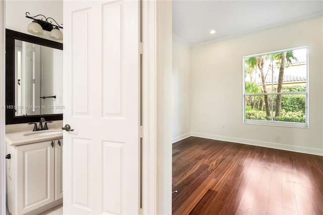 bathroom with baseboards, ornamental molding, wood finished floors, vanity, and recessed lighting