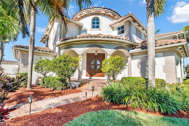 mediterranean / spanish home featuring a tile roof and stucco siding