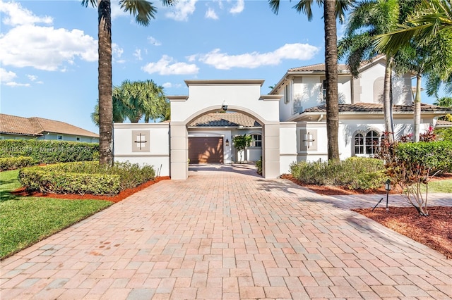 mediterranean / spanish home featuring decorative driveway, a tile roof, and stucco siding